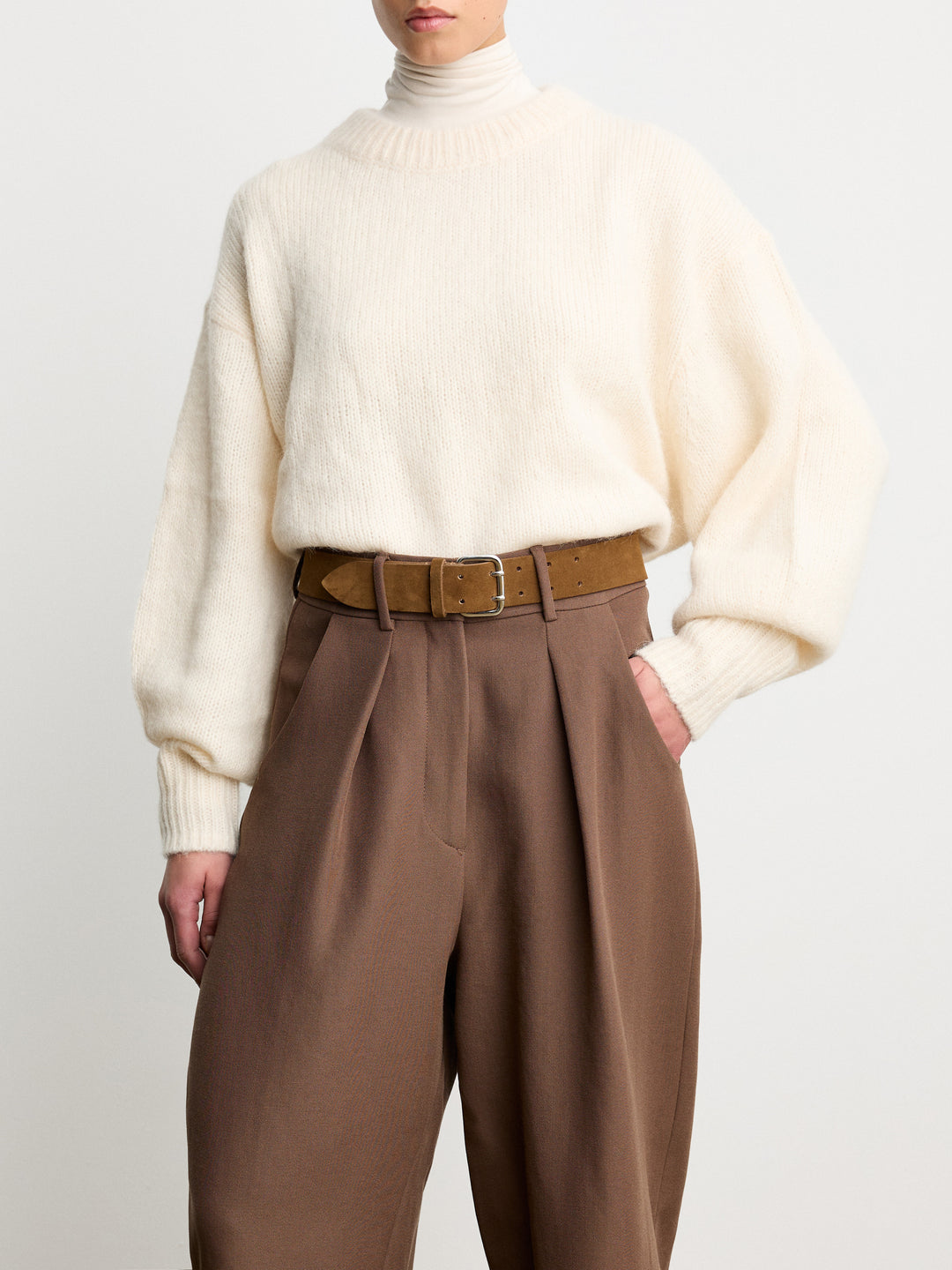 Déhanche Hutch Suede Belt - Luxurious brown suede belt with silver buckle, styled with brown pleated trousers and a cozy cream sweater for an elegant look.