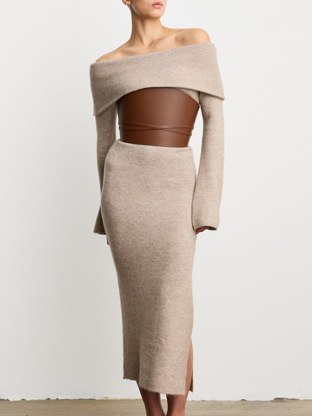 Déhanche undone leather corset in brown, styled with beige off-shoulder dress. Elegant and chic fashion statement for women.