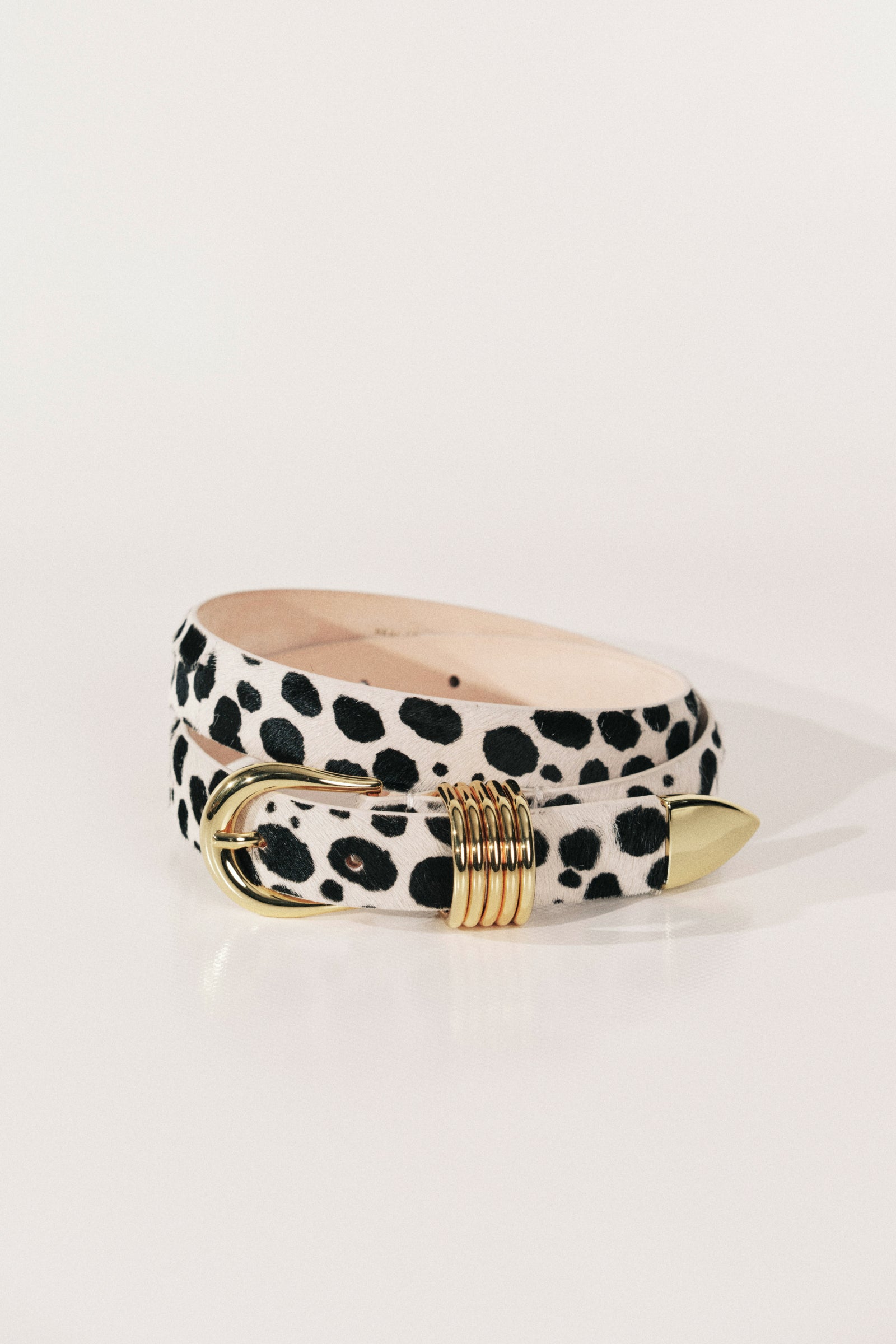 A belt with a black-on-white dalmatian pattern and gold-tone hardware.
