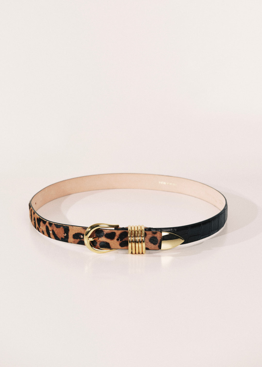 A belt with a leopard print pattern on one side, a solid black finish on the other, and gold-tone hardware, displayed on a clean white background.
