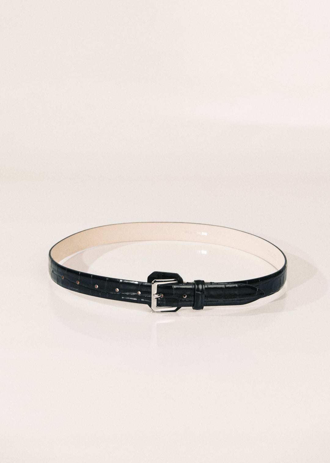 A black leather belt with a silver buckle, displayed in a circular shape on a clean white studio background.