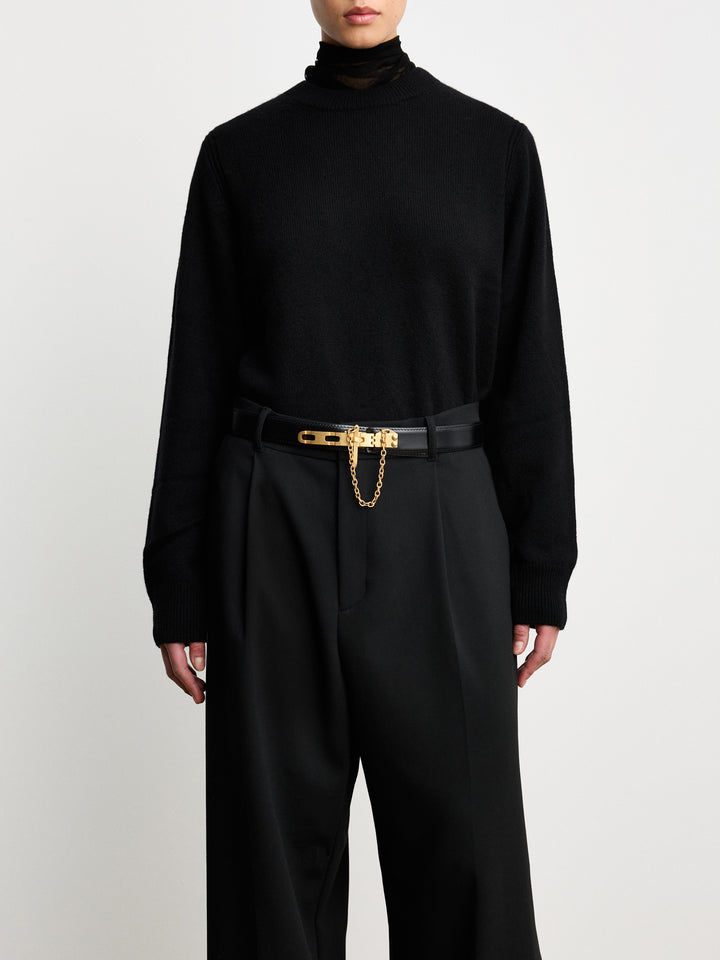 Déhanche Artemisia black leather belt with gold buckle and chain, paired with a chic black blazer, showcasing a sophisticated and elegant look.