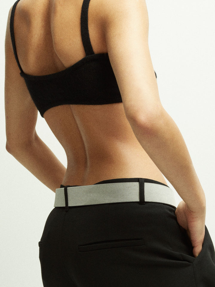 Close-up of a model wearing Déhanche hutch suede pants with a light grey belt and a black crop top, highlighting contemporary and sophisticated fashion.