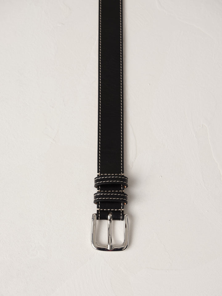 Déhanche Louison black leather belt with white stitching and silver buckle, displayed against a light background.