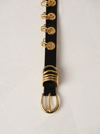 Déhanche Revenge Gold black leather belt with gold grommets and buckle, displayed against a light background.
