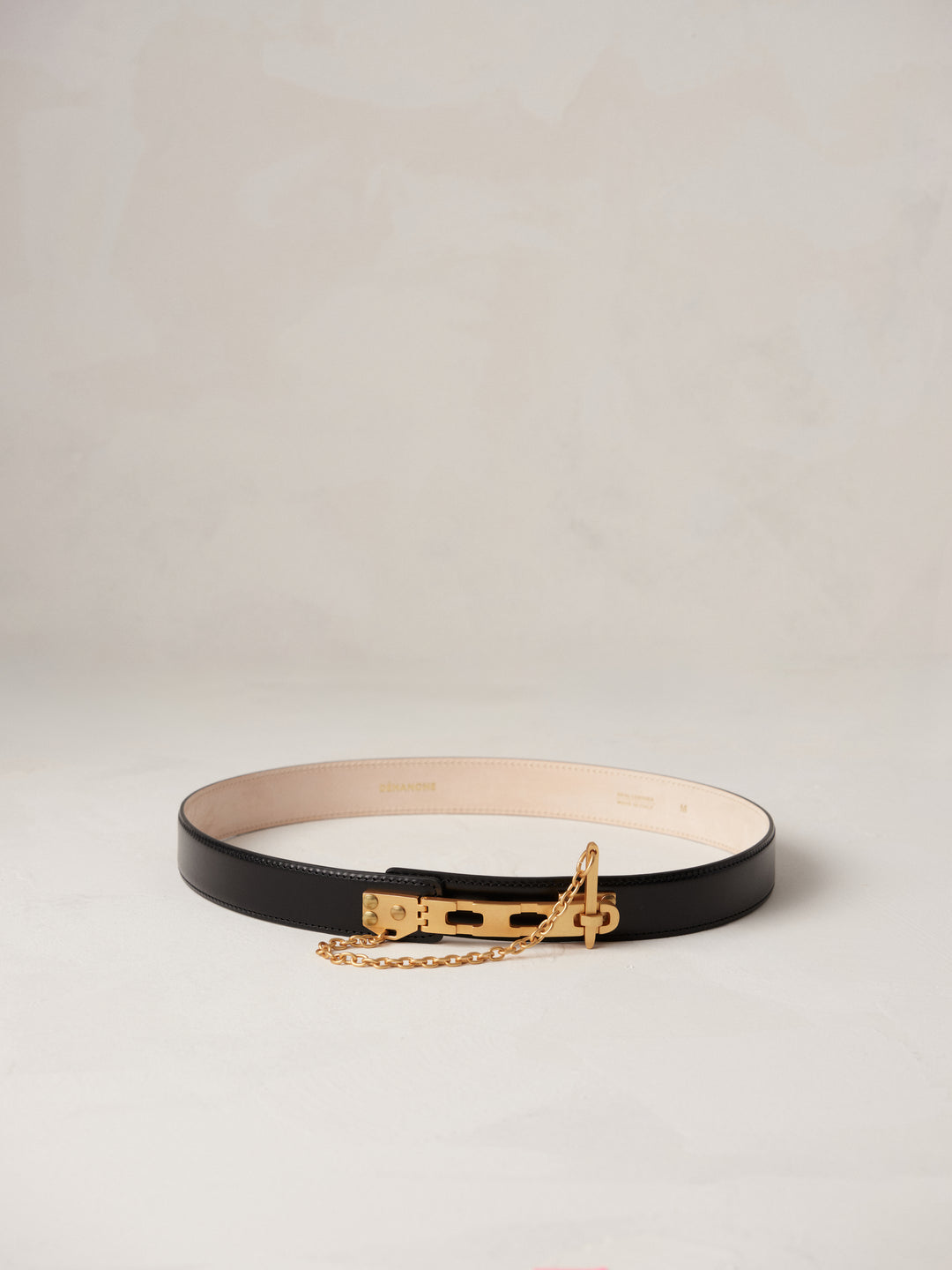 Déhanche Artemisia black leather belt with gold buckle and chain, featuring a minimalist design. Perfect accessory for elegant and chic outfits.