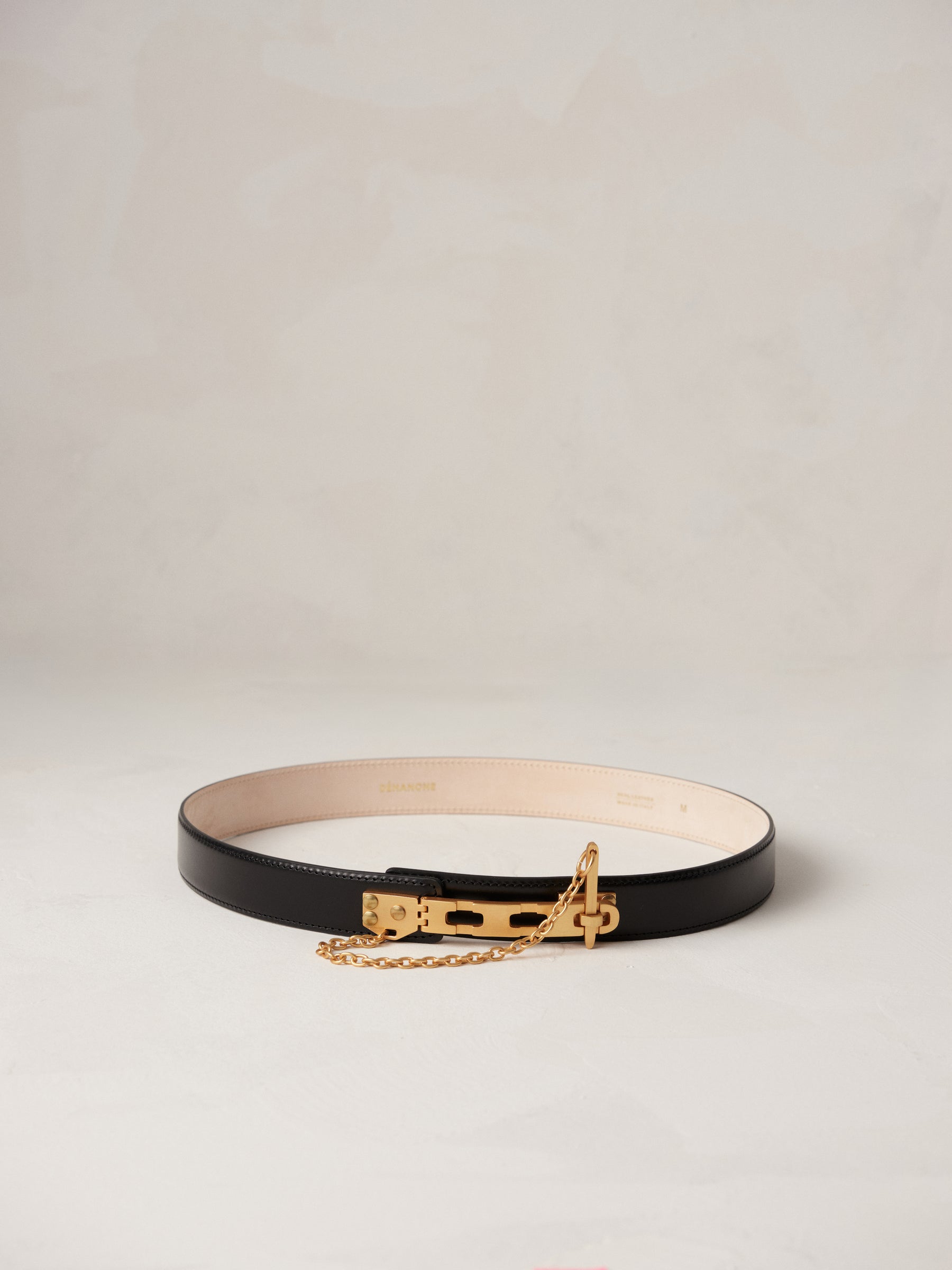 Déhanche Artemisia black leather belt with gold buckle and chain, featuring a minimalist design. Perfect accessory for elegant and chic outfits.