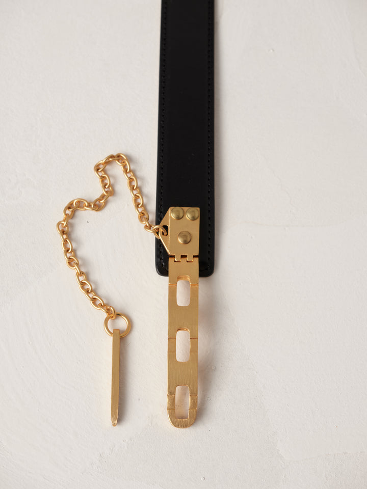 Close-up of Déhanche Artemisia belt, featuring a sleek black leather strap with a distinctive gold chain and hardware, showcasing elegance and sophistication.
