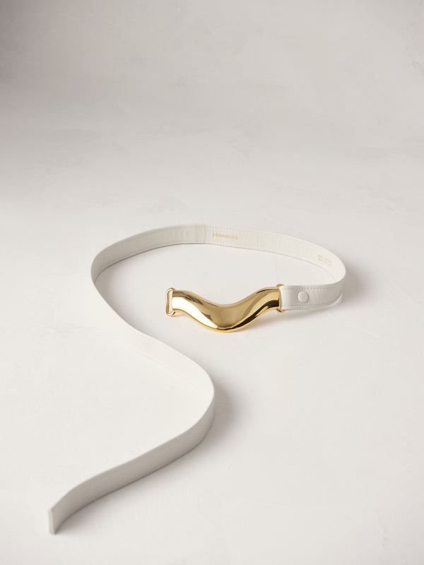 Déhanche Brancusi belt in crisp white leather, featuring a distinctive sculptural gold centerpiece, blending contemporary style with refined elegance.
