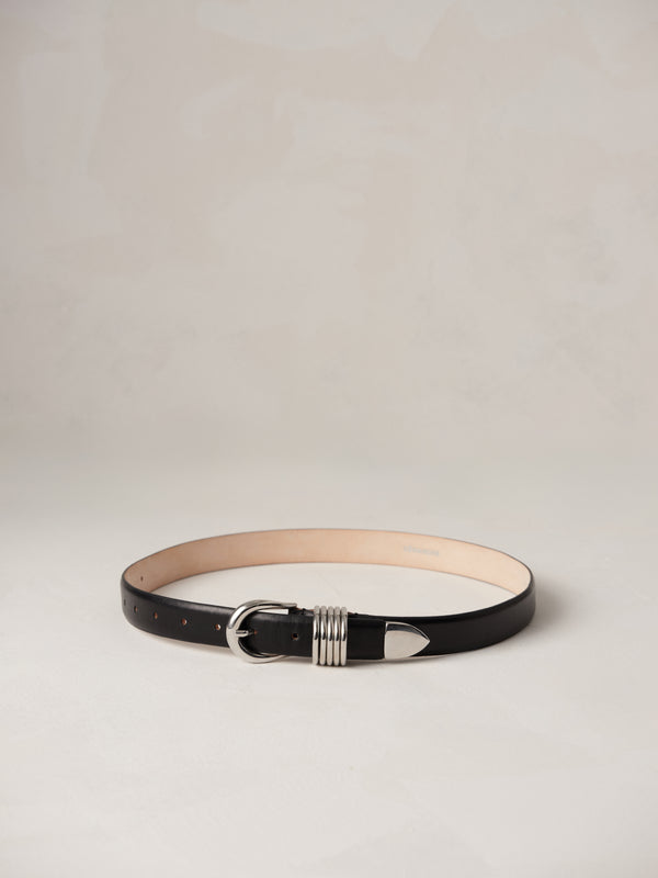 Déhanche Hollyhock belt in sleek black leather, featuring a distinctive silver buckle with intricate detailing, blending classic elegance with modern style.