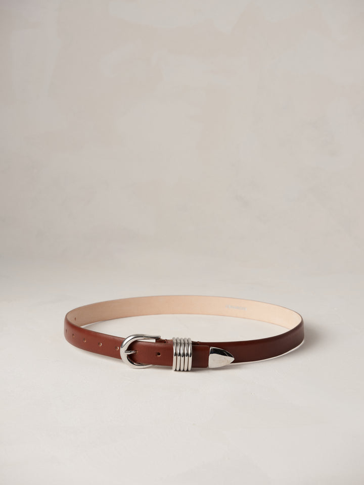 Déhanche Hollyhock belt in rich brown leather, featuring an intricate silver buckle, blending classic elegance with modern style.