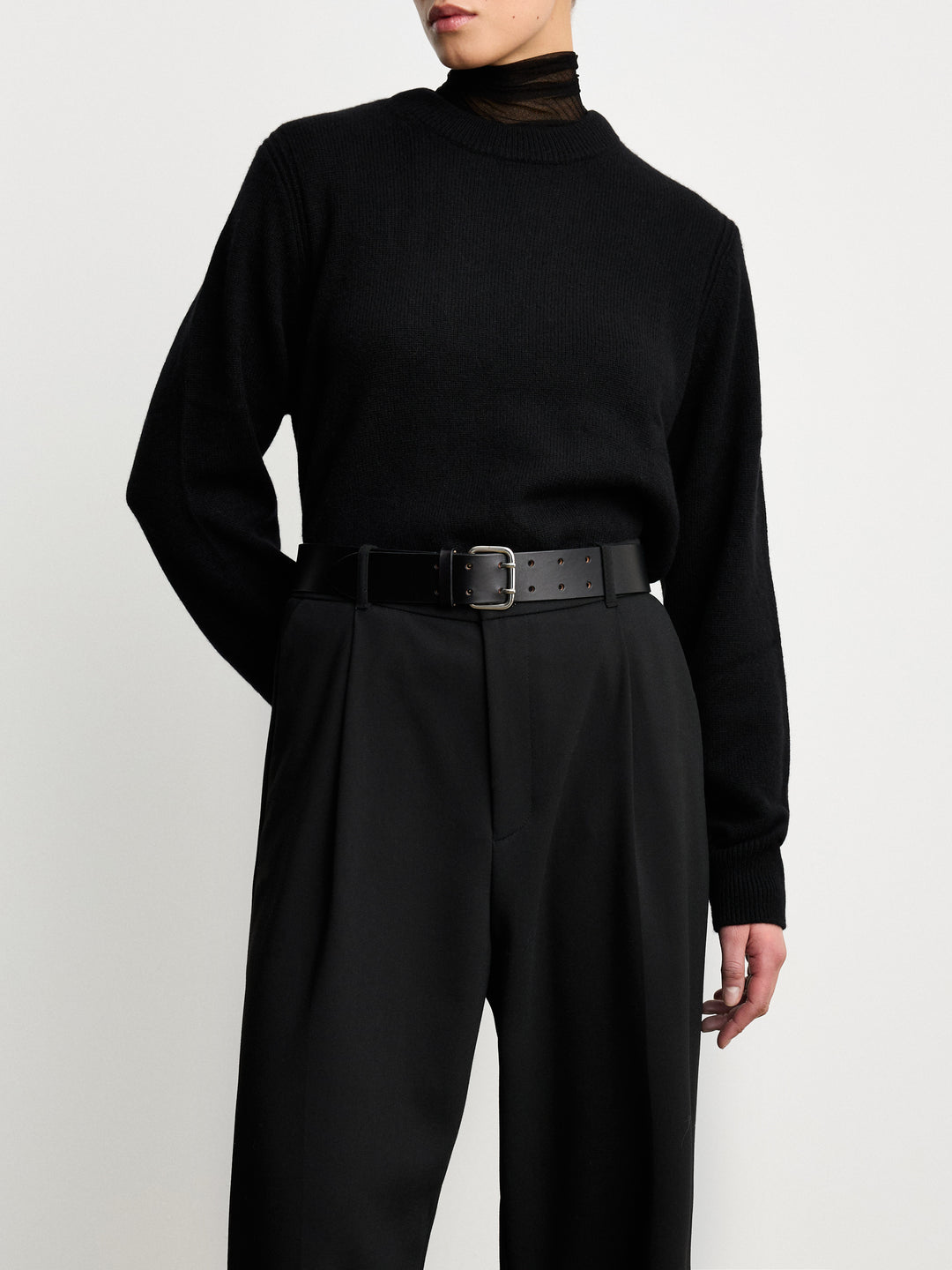 Déhanche Hutch Leather Belt - Classic black leather belt with silver buckle, paired with black trousers and a black sweater. Ideal for a sophisticated, monochromatic look.