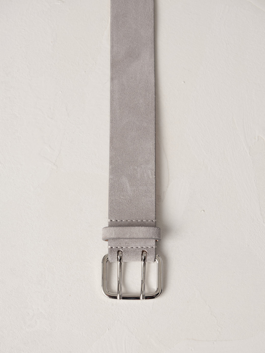 Close-up of Déhanche hutch suede belt in light grey with a silver buckle, emphasizing the luxurious suede material and elegant design details.
