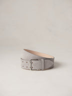 Déhanche hutch suede belt in light grey, elegantly coiled on a neutral background, featuring a sleek silver buckle and premium craftsmanship.