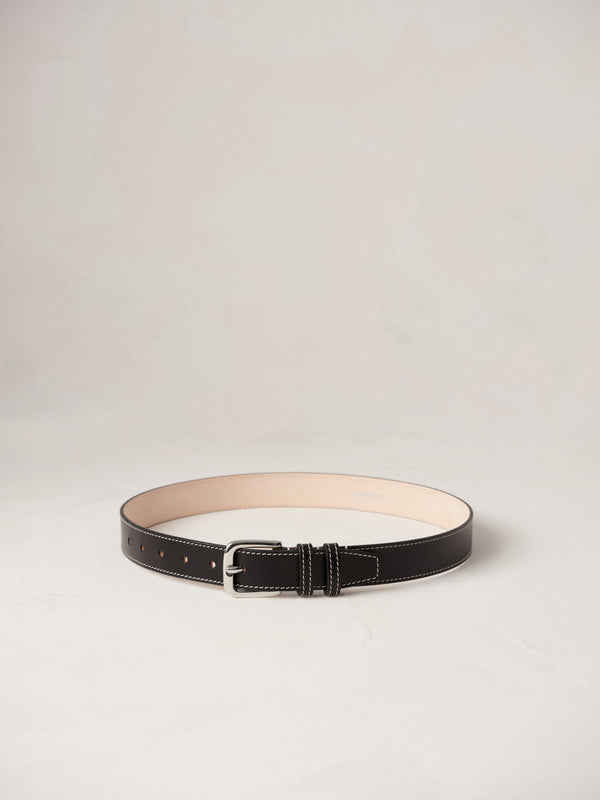 Déhanche Louison black leather belt with white stitching and silver buckle, displayed against a light background.