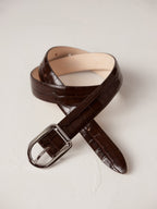 Déhanche Mija Croco brown leather belt with crocodile texture and silver buckle, displayed against a light background.