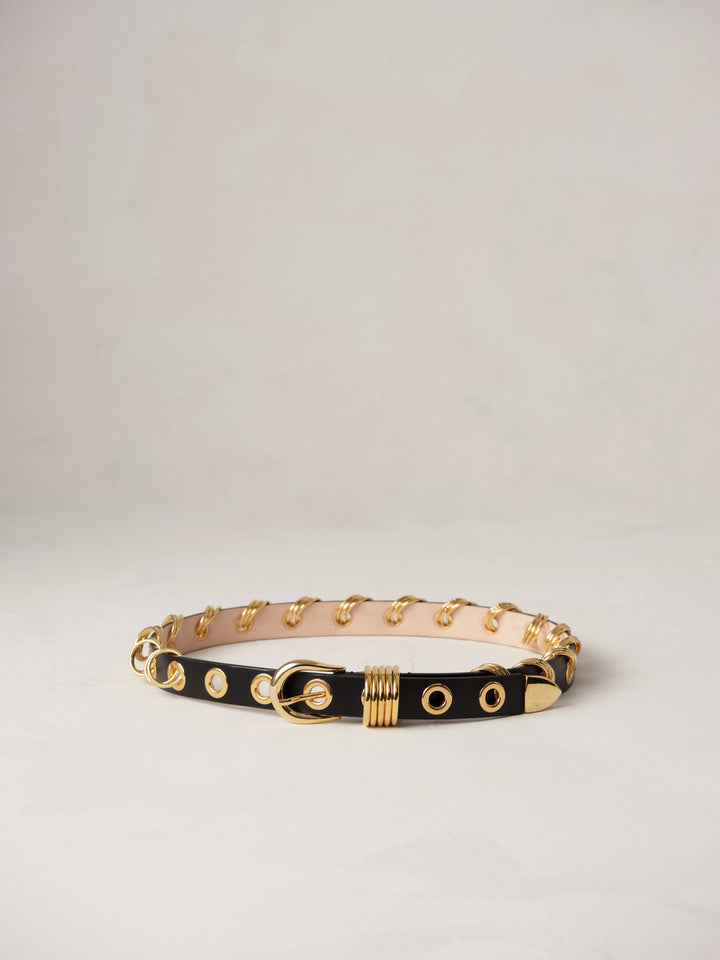 Déhanche Revenge Gold black leather belt with gold grommets and buckle, displayed against a light background.