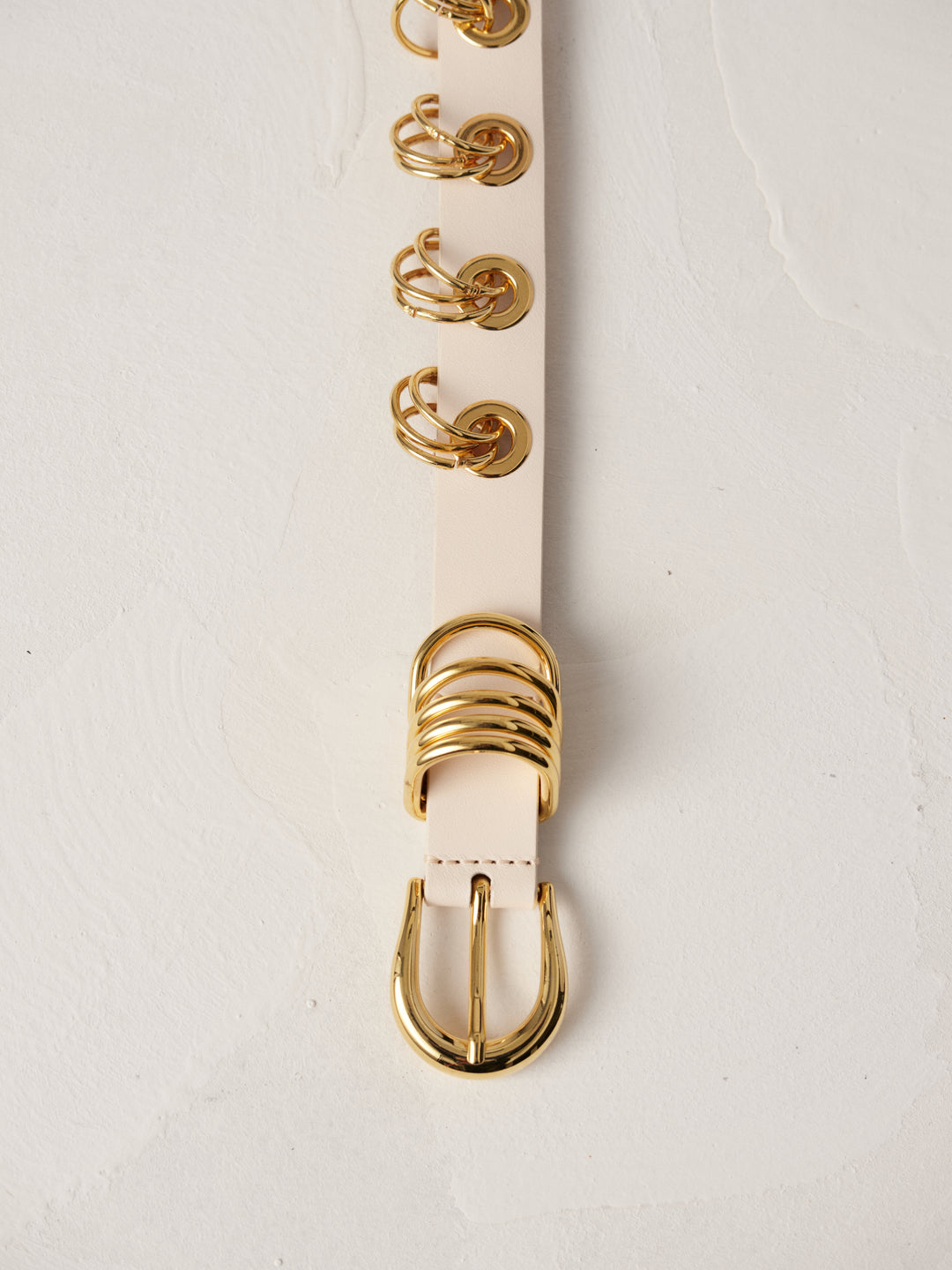 Déhanche Revenge Gold white leather belt with gold grommets and buckle, displayed against a light background.