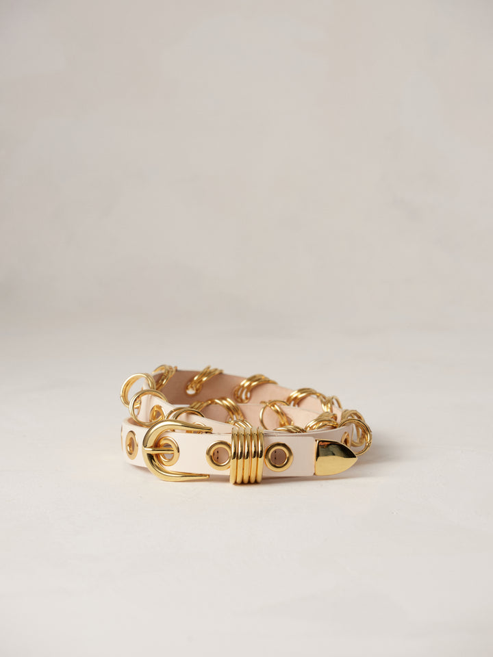 Déhanche Revenge Gold white leather belt with gold grommets and buckle, displayed against a light background.