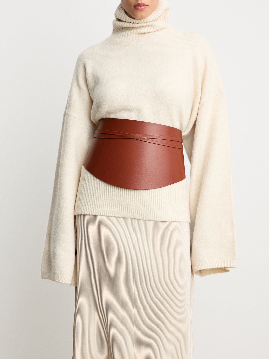 Déhanche Undone Corset in brown leather, worn over a cream turtleneck sweater and ribbed skirt, showcasing a chic and elegant front view.
