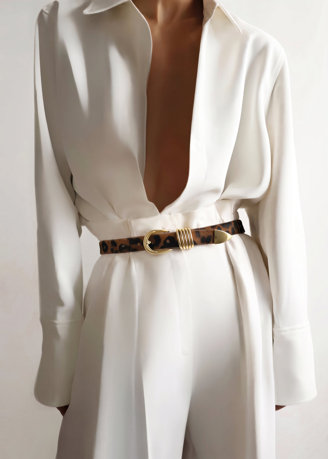 Model wearing a white outfit with a jaguar print belt featuring gold hardware