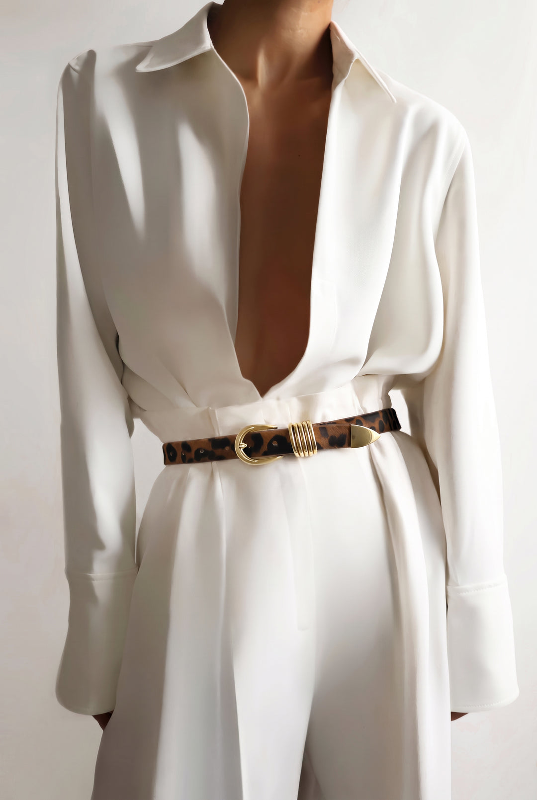 Model wearing a white outfit with a jaguar print belt featuring gold hardware