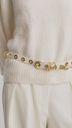 Model wearing Déhanche Revenge Gold white leather belt with gold grommets and buckle, styled with cream trousers and a cream sweater.