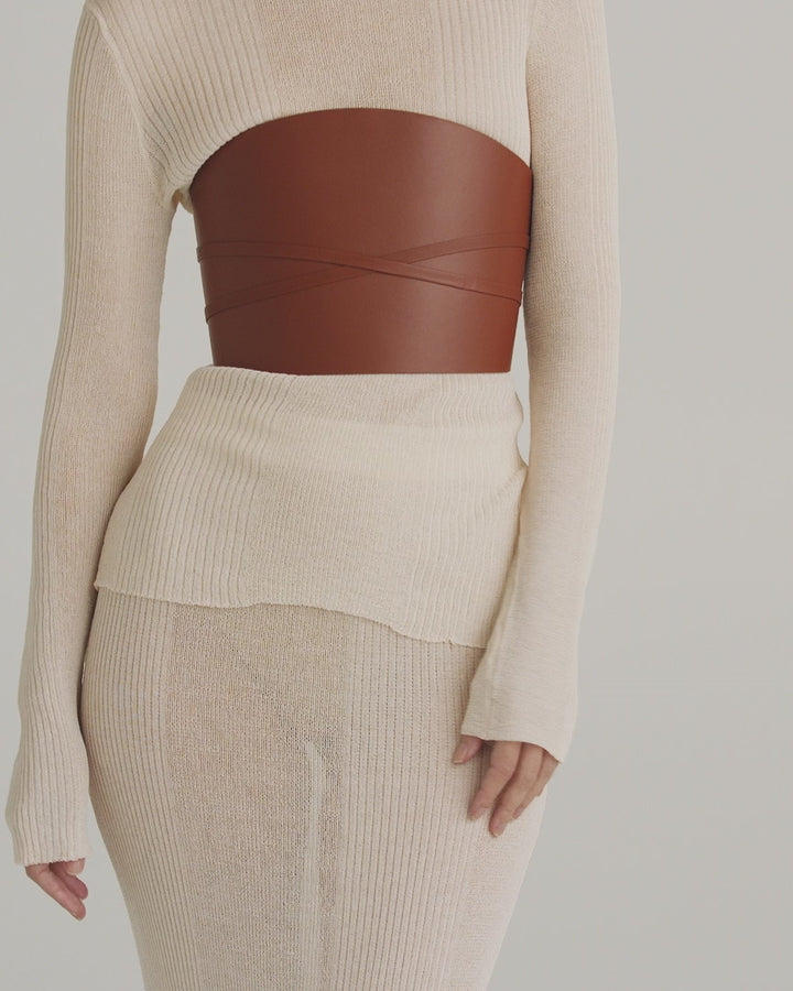 Déhanche Undone Corset in brown leather, styled over a cream knitted dress with long sleeves and high neckline, highlighting a chic front view.