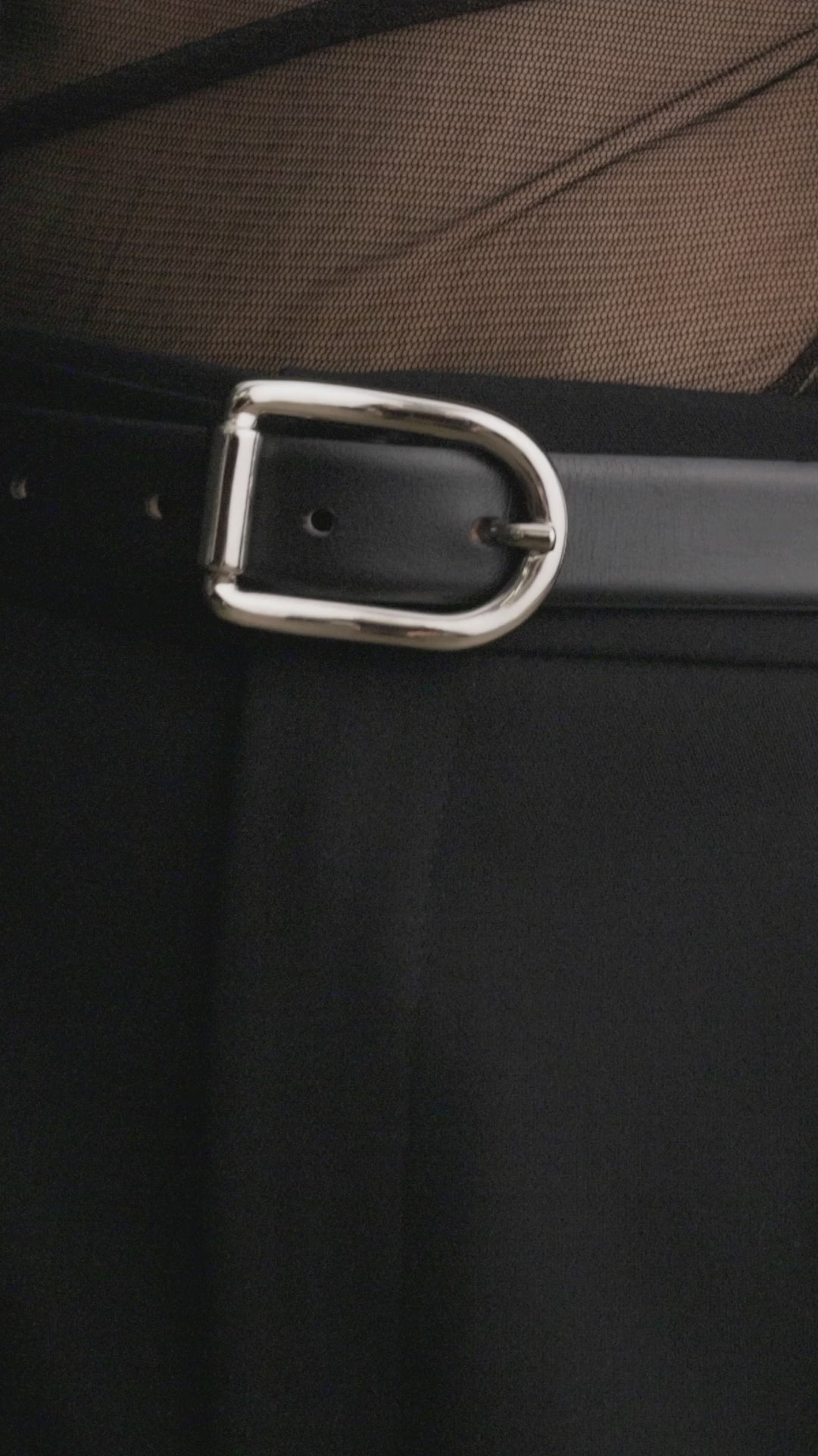 Model wearing Déhanche Mija black leather belt with silver buckle, styled with black trousers, a sheer black top, and an oversized black blazer.