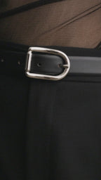 Model wearing Déhanche Mija black leather belt with silver buckle, styled with black trousers, a sheer black top, and an oversized black blazer.