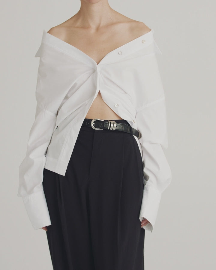 Déhanche Hollyhock Croco belt in black crocodile leather with silver buckle, paired with an off-shoulder white shirt and black pants for an edgy look.