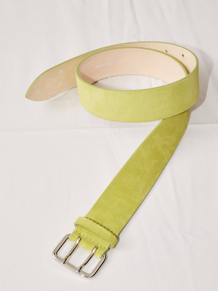 Déhanche hutch suede belt in light green, coiled on a white surface, featuring a silver buckle and showcasing premium quality and elegant design.