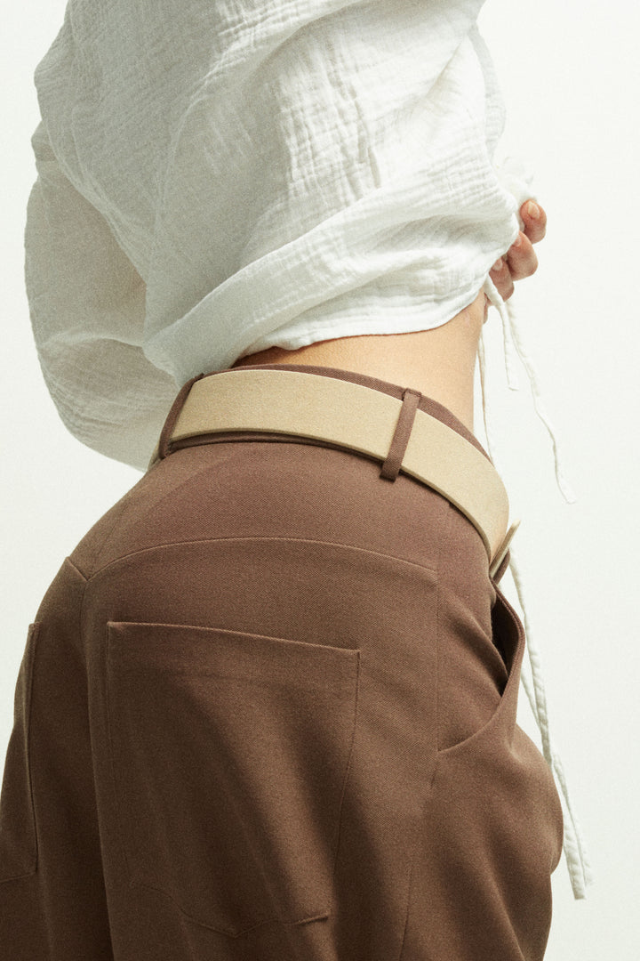 Déhanche Hutch Suede Belt - Natural beige suede belt styled with high-waisted brown pants and a white blouse, showcasing the belt's elegant design and versatile color.